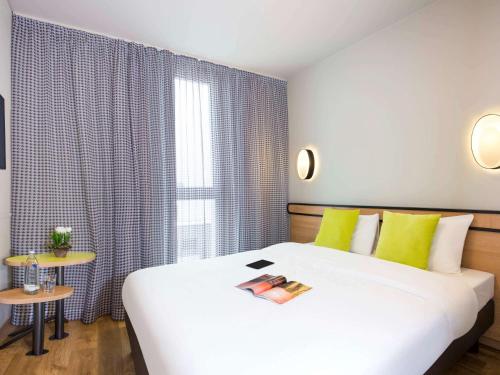 Un dormitorio con una gran cama blanca y una ventana en Aparthotel Adagio access München City Olympiapark, en Múnich
