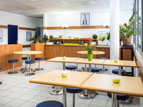 une cafétéria avec des tables et des chaises et une cuisine dans l'établissement ibis budget Béziers Centre Palais Congres, à Béziers