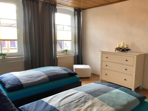 a bedroom with two beds and a dresser and two windows at 100qm Ferienwohnung in Halberstadt, dem Tor zum Harz in Halberstadt