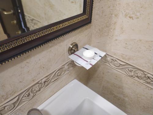 a bathroom with a white sink and a mirror at VLG Hotel in Boryspilʼ