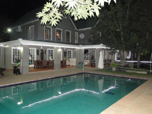 a swimming pool in front of a house at night at Highlands Creek Self Catering Accommodation in Nelspruit