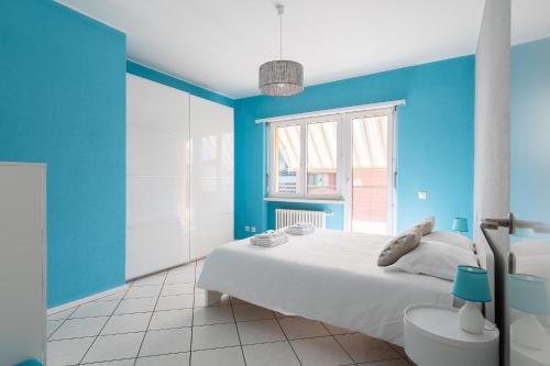 a blue bedroom with a white bed and a window at Lido Apartments by Quokka 360 - 5 min from the centre and the Lugano Lido in Lugano