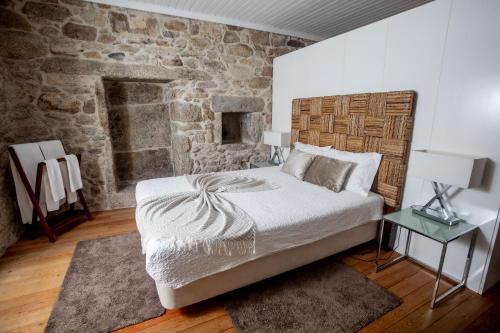 a bedroom with a bed and a stone wall at Casas de São Martinho in Arcos de Valdevez