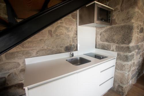 - une cuisine avec un évier et un mur en pierre dans l'établissement Casas de São Martinho, à Arcos de Valdevez