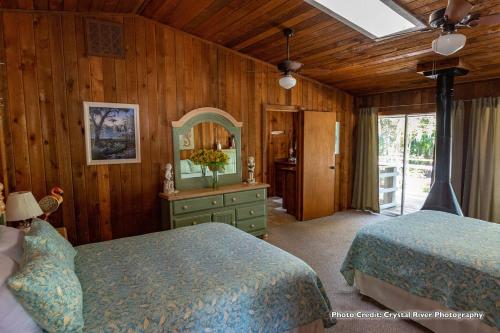 a bedroom with two beds and a dresser with a mirror at Riverfront Treetop Bungalow in Homosassa