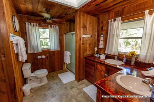 a wooden bathroom with a toilet and a sink at Riverfront Treetop Bungalow in Homosassa