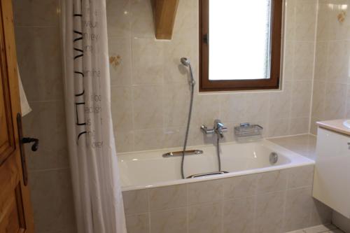 a bathroom with a bath tub with a shower curtain at La Ferme de Sous-Lachat in Samoëns