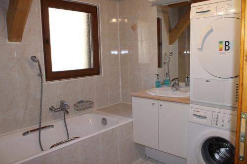 a bathroom with a tub and a sink and a washing machine at La Ferme de Sous-Lachat in Samoëns