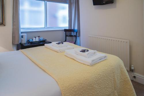 a bed with two towels on top of it at Arlana Guest House in Cleethorpes