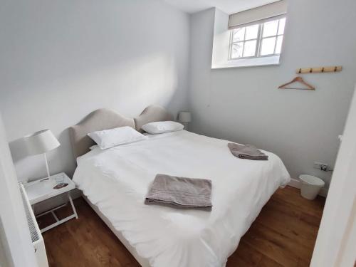 a white bedroom with a large white bed with a window at Rose Barn in West Lavington