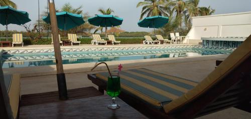 a drink sitting on a table next to a swimming pool at Hôtel Katakalousse in Yembakana