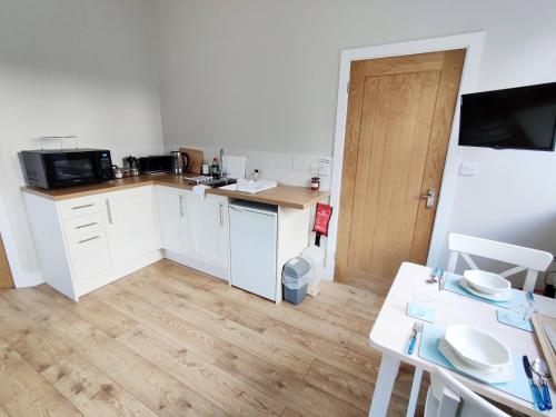 a kitchen with white cabinets and a wooden floor at Rose Barn in West Lavington