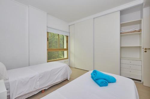 a white bedroom with two beds and a mirror at Albar Club de Mar in Pinamar