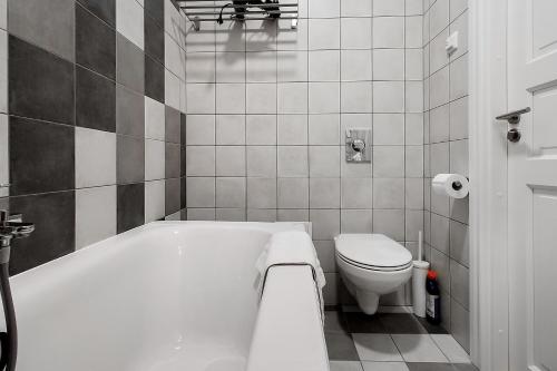 a white bathroom with a tub and a toilet at Residential Barona Apartments in Riga Centre in Rīga