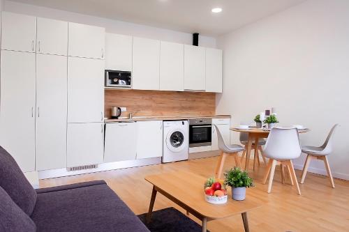 a kitchen with white cabinets and a table and chairs at Residential Barona Apartments in Riga Centre in Rīga