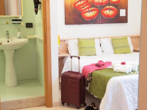 a bedroom with a bed with a suitcase next to a sink at Locanda Lighea Rooms in San Vito lo Capo