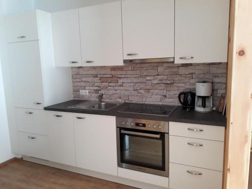 a kitchen with white cabinets and a stove top oven at Singerhof in Fulpmes