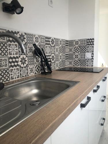 - une cuisine avec un évier en acier inoxydable et du carrelage dans l'établissement Charmant appartement au coeur de Bayeux, à Bayeux
