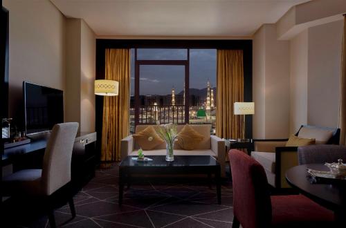 a living room with a couch and a table and a window at Pullman Zamzam Madina in Al Madinah
