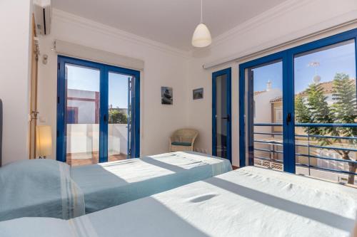 una camera da letto con due letti e una grande finestra di Villa Blue Garden by ALGARVEMANTA a Manta Rota
