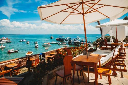 a restaurant with tables and chairs and the ocean at Hotel Portaló in Morro de São Paulo