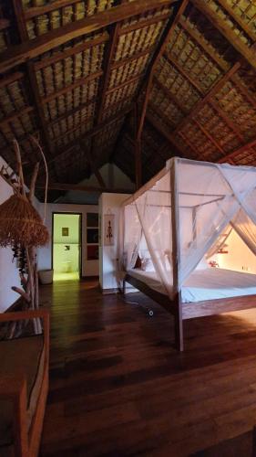 Zimmer mit einem Bett und Holzboden in der Unterkunft LE TRANSAT in Ambatoloaka
