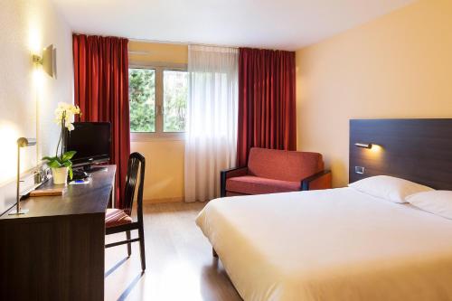 a hotel room with a bed and a chair at Oceania Quimper in Quimper