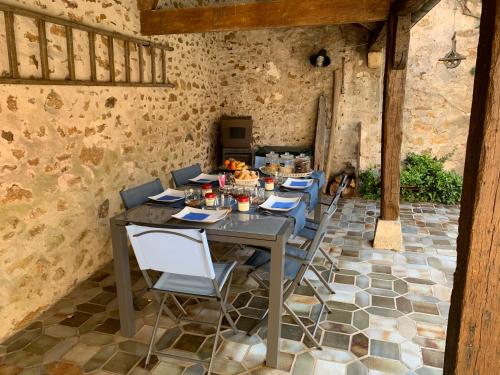 une table et des chaises dans une pièce avec un mur en pierre dans l'établissement La Maison d'Emilie - Chambres d'hôtes, à Chaumes-en-Brie