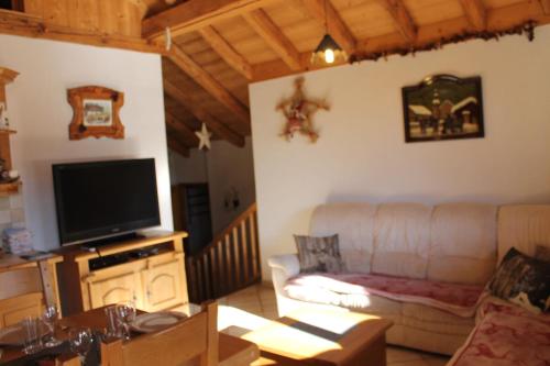 a living room with a couch and a flat screen tv at La Ferme de Sous-Lachat in Samoëns