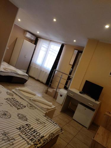 a room with two beds and a desk and a television at Pensiunea B&B Casa Italia in Timişoara
