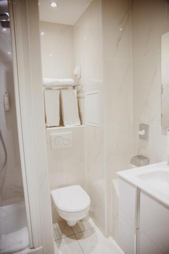 a white bathroom with a toilet and a sink at Arcadie Montparnasse in Paris