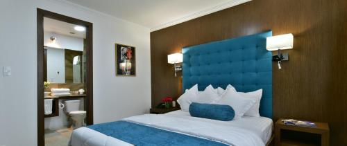 1 dormitorio con 1 cama grande y cabecero azul en Hotel Gran Mariscal Quito, en Quito