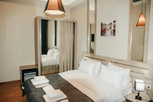 a bedroom with a bed with white pillows and a mirror at City Heart Hotel in Tbilisi City