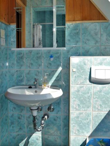 a blue tiled bathroom with a sink and a mirror at Zur Sonne in Freest