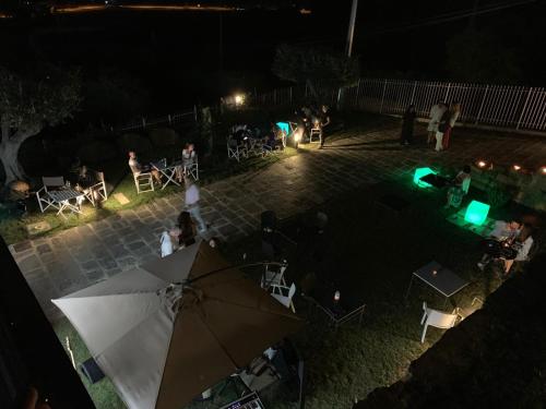 HOTEL MYRTUS في أغروبولي: مجموعة من الناس يجلسون في الفناء في الليل