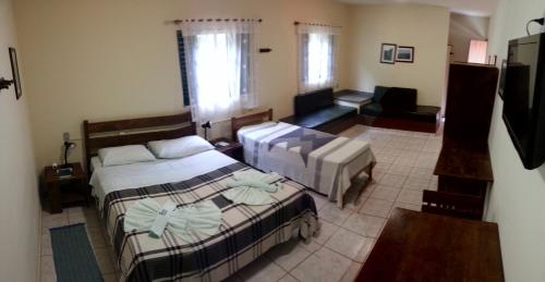 a bedroom with two beds and a living room at Pousada Barcelos in São Roque de Minas