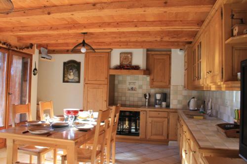a kitchen with a wooden table and a wooden ceiling at La Ferme de Sous-Lachat in Samoëns