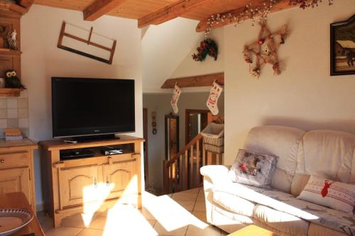 a living room with a couch and a television at La Ferme de Sous-Lachat in Samoëns