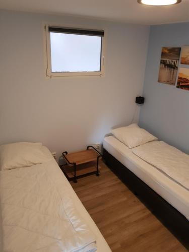 1 dormitorio con 2 camas y ventana en Vakantiewoning Koegras en Julianadorp