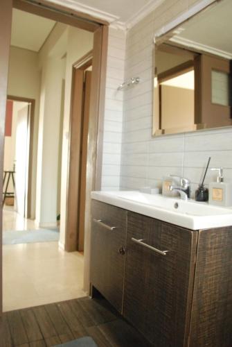 een badkamer met een wastafel en een spiegel bij Emerald 110m2 entire floor apt steps to city’s heart in Kalamata