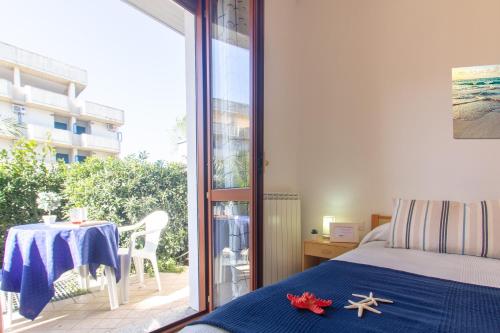 - une chambre avec un lit et un balcon avec une table dans l'établissement Appartamento La Pineta Sud - MyHo Casa, à Martinsicuro