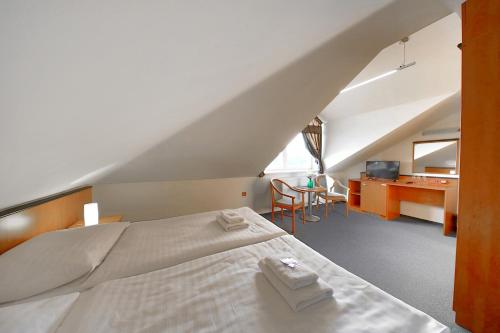 a bedroom with a bed with two towels on it at Hotel BRADA in Jičín