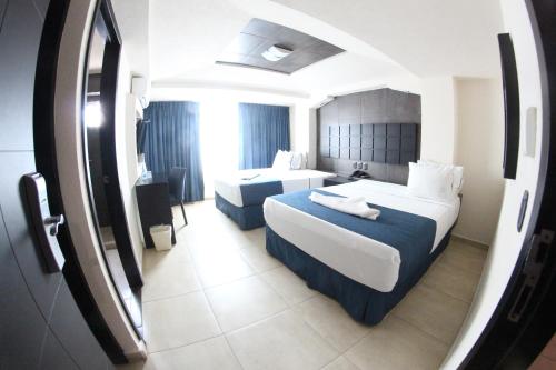 Una habitación de hotel con dos camas y un espejo. en Hotel Portonovo Plaza Malecon, en Puerto Vallarta