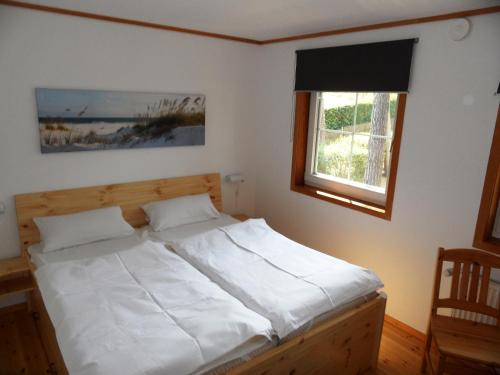 a bedroom with a bed with white sheets and a window at ökologische Ferienanlage in Bansin