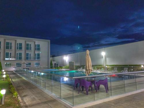 a swimming pool at night with a table and umbrella at Hotel Las Olas Palermo in Neiva