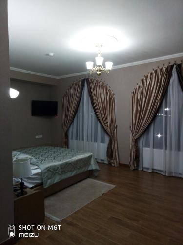a bedroom with a bed and two large windows at Старый Бастион in Bender