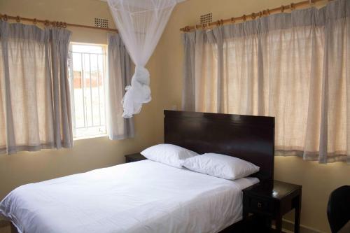 Chrinas Guest House في ليلونغوي: غرفة نوم بسرير وملاءات بيضاء ونافذة