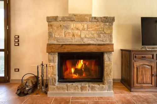 a stone fireplace in a living room with a television at Villa Viktoria & Andras in Tredozio