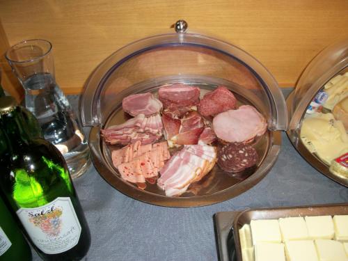 a pan filled with meat and other foods next to a bottle of wine at Weingut und Gästehaus Salzl in Illmitz