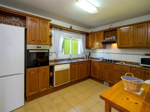 cocina con armarios de madera y nevera blanca en Holiday Home Envalira, en Cunit
